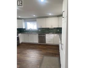 A kitchen with white cabinets and a wooden floor.