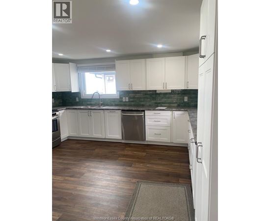 A kitchen with white cabinets and a wooden floor.