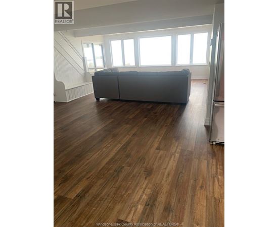 A living room with a grey couch and wooden floors.