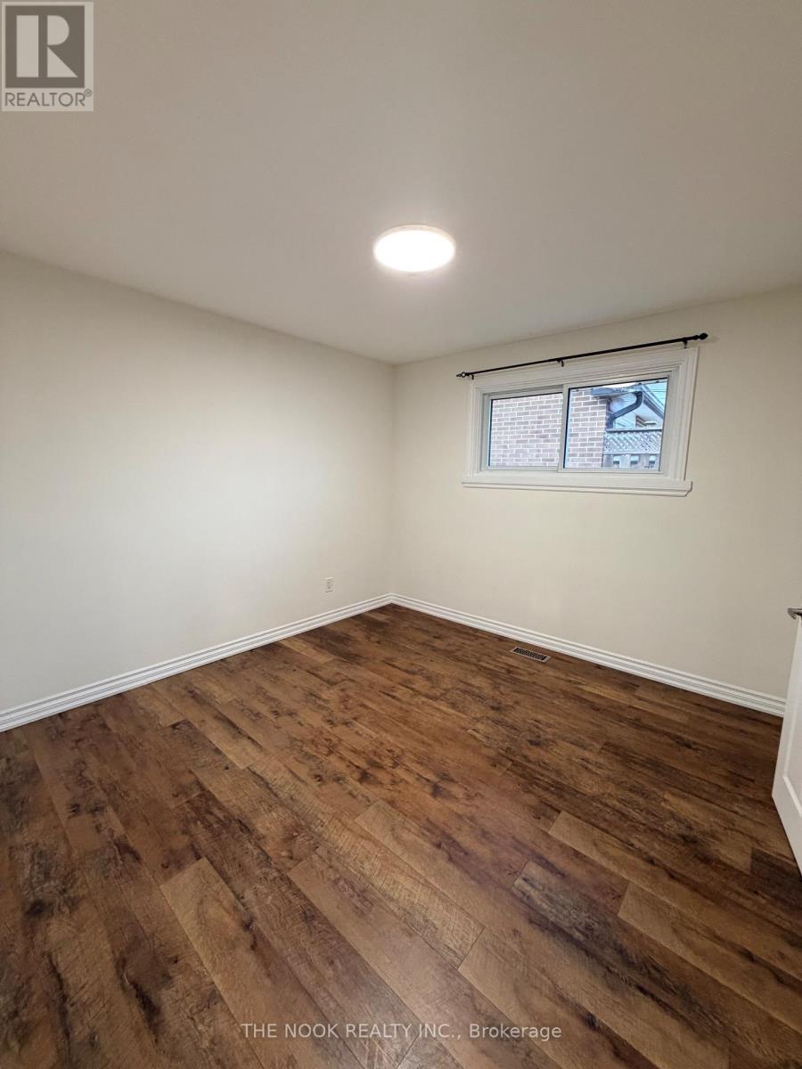 A room with wooden flooring and a window showing a building outside.