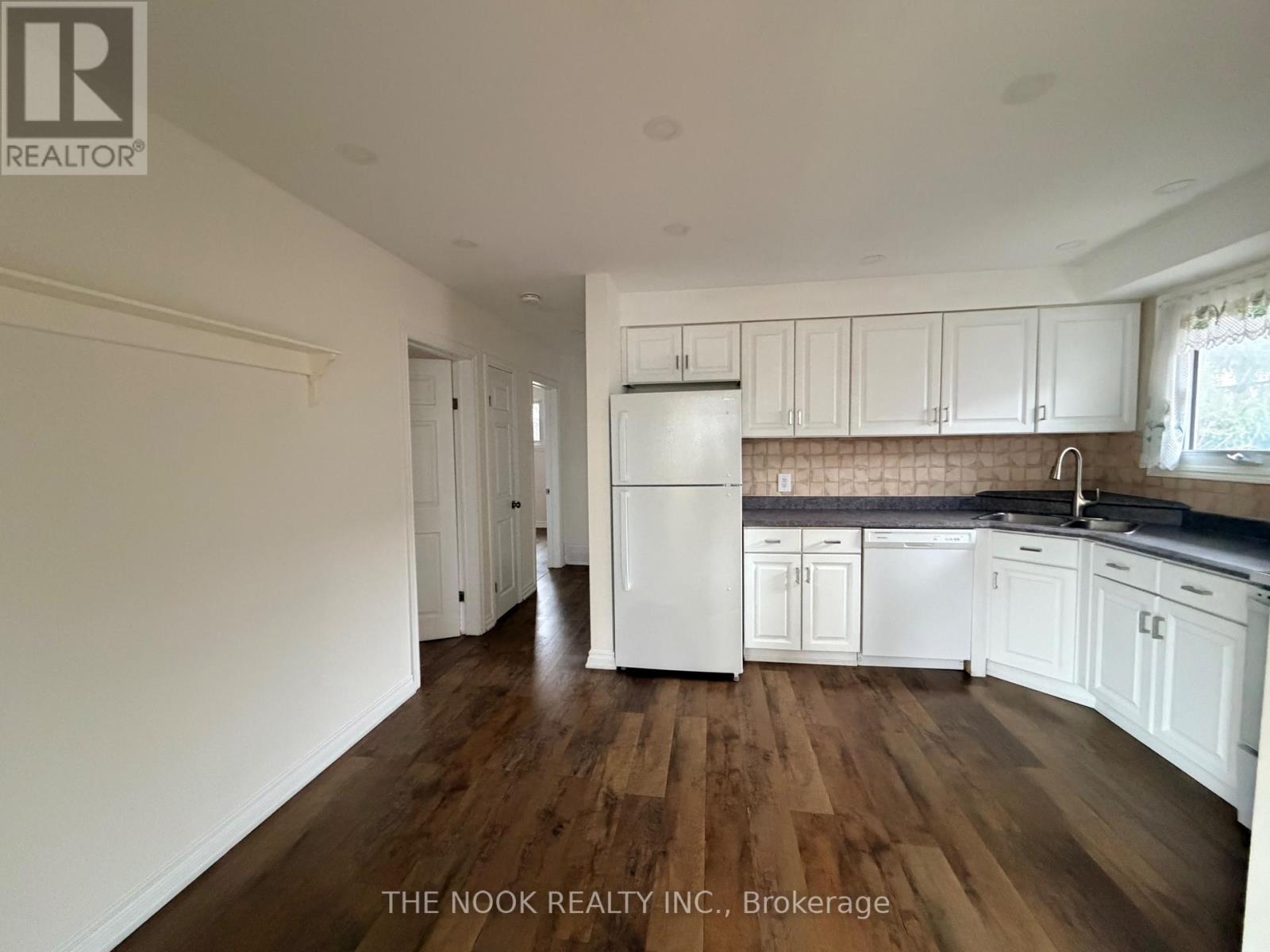 A kitchen with white cabinets and a refrigerator.