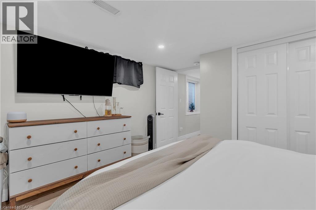 A bedroom with a large bed, a dresser with a flat screen TV above it, and a window with a view of the outdoors.