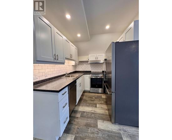 A kitchen with white cabinets and a black fridge.