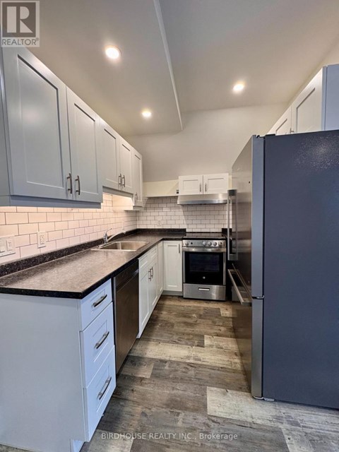 A kitchen with white cabinets and a black fridge.