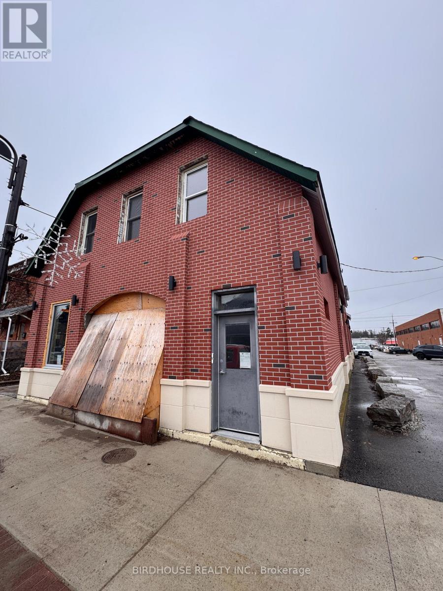 A red brick building with a large door and a sign that says Birdhouse Realty Inc Brokerage.
