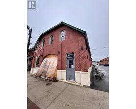 A red brick building with a large door and a sign that says Birdhouse Realty Inc Brokerage.