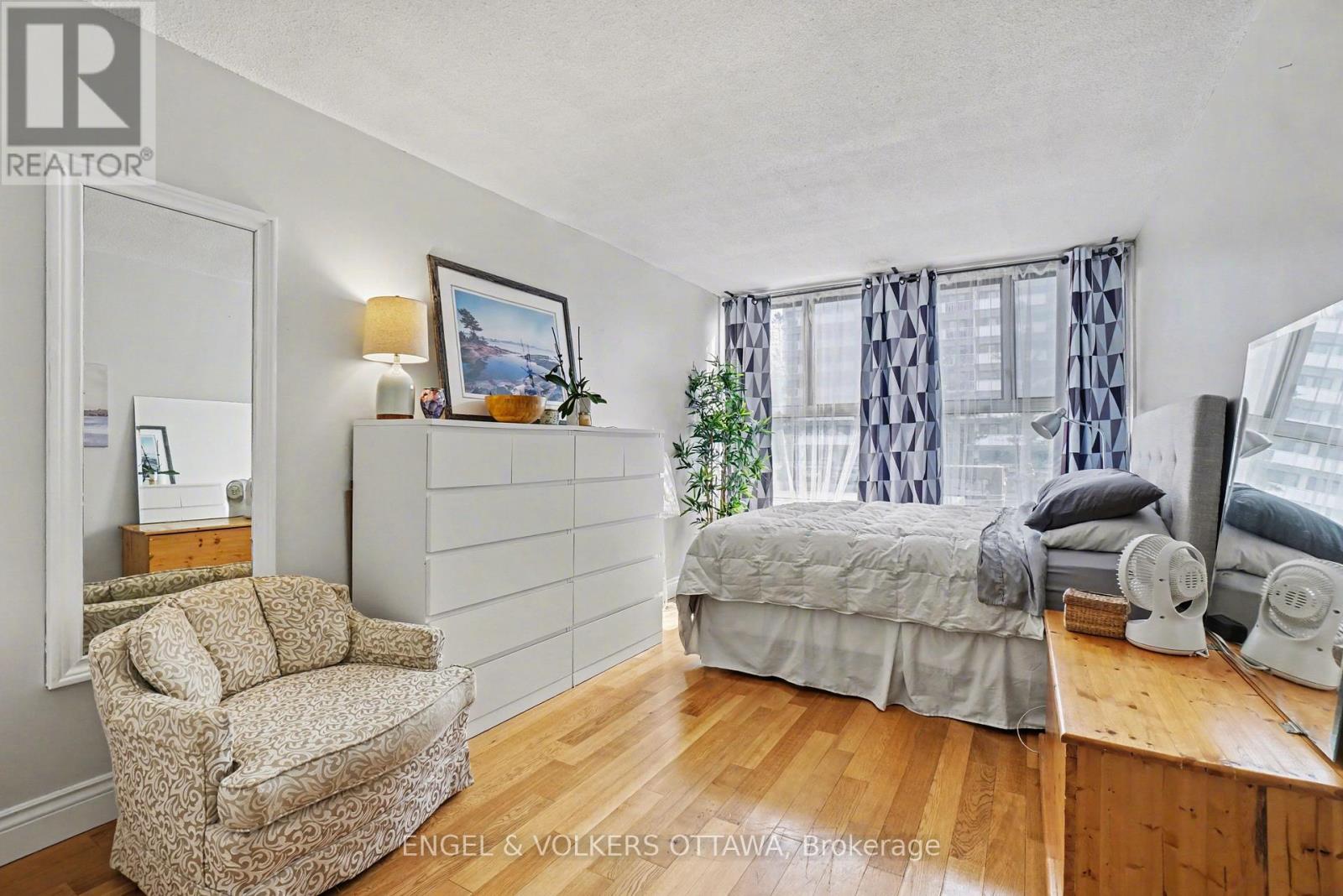 A bedroom with a bed, chair, and window.