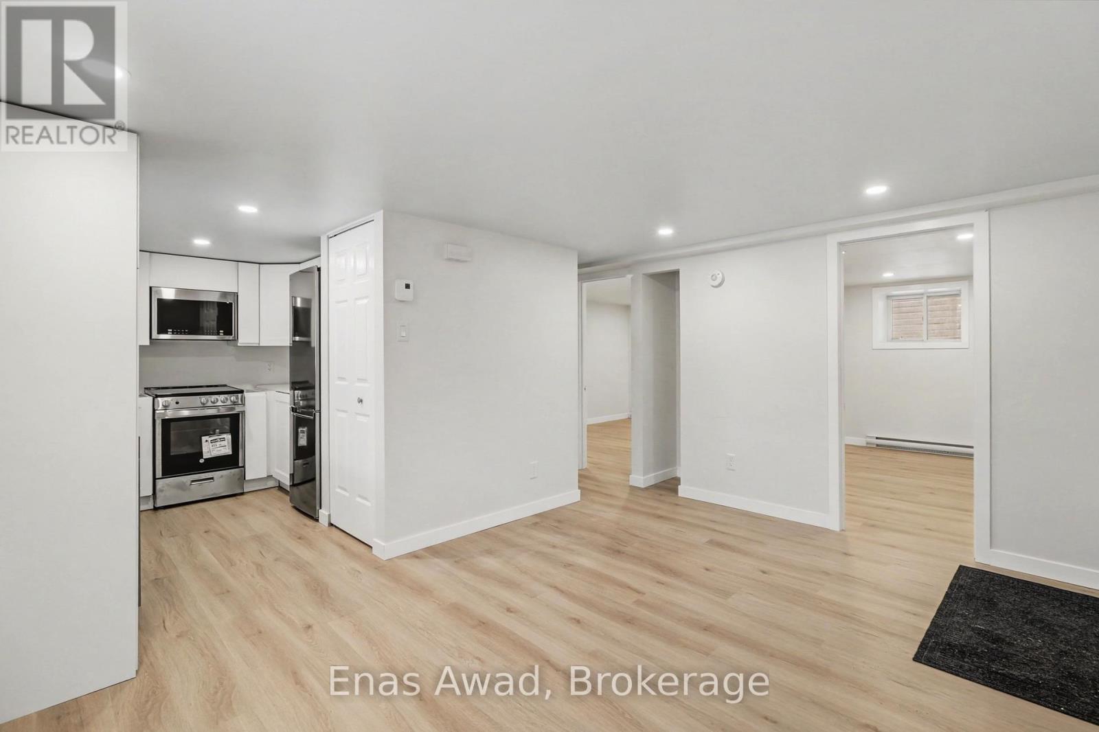 A spacious, well-lit kitchen with wooden floors and white walls.