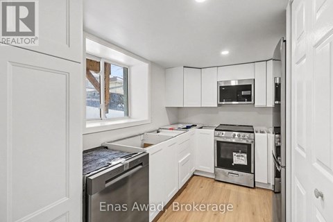 A white kitchen with a stove top oven and a microwave above the stove.