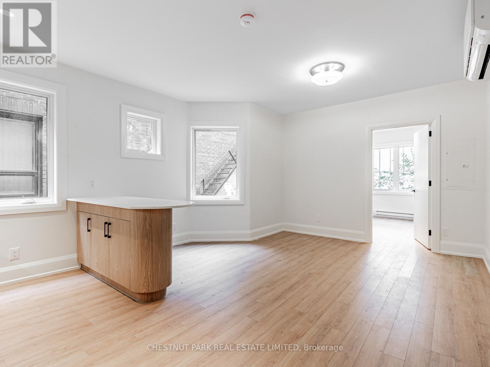 A spacious room with wood flooring and white walls.