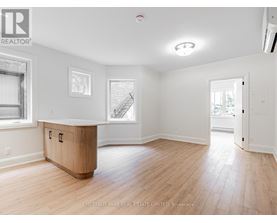 A spacious room with wood flooring and white walls.