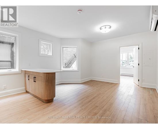 A spacious room with wood flooring and white walls.