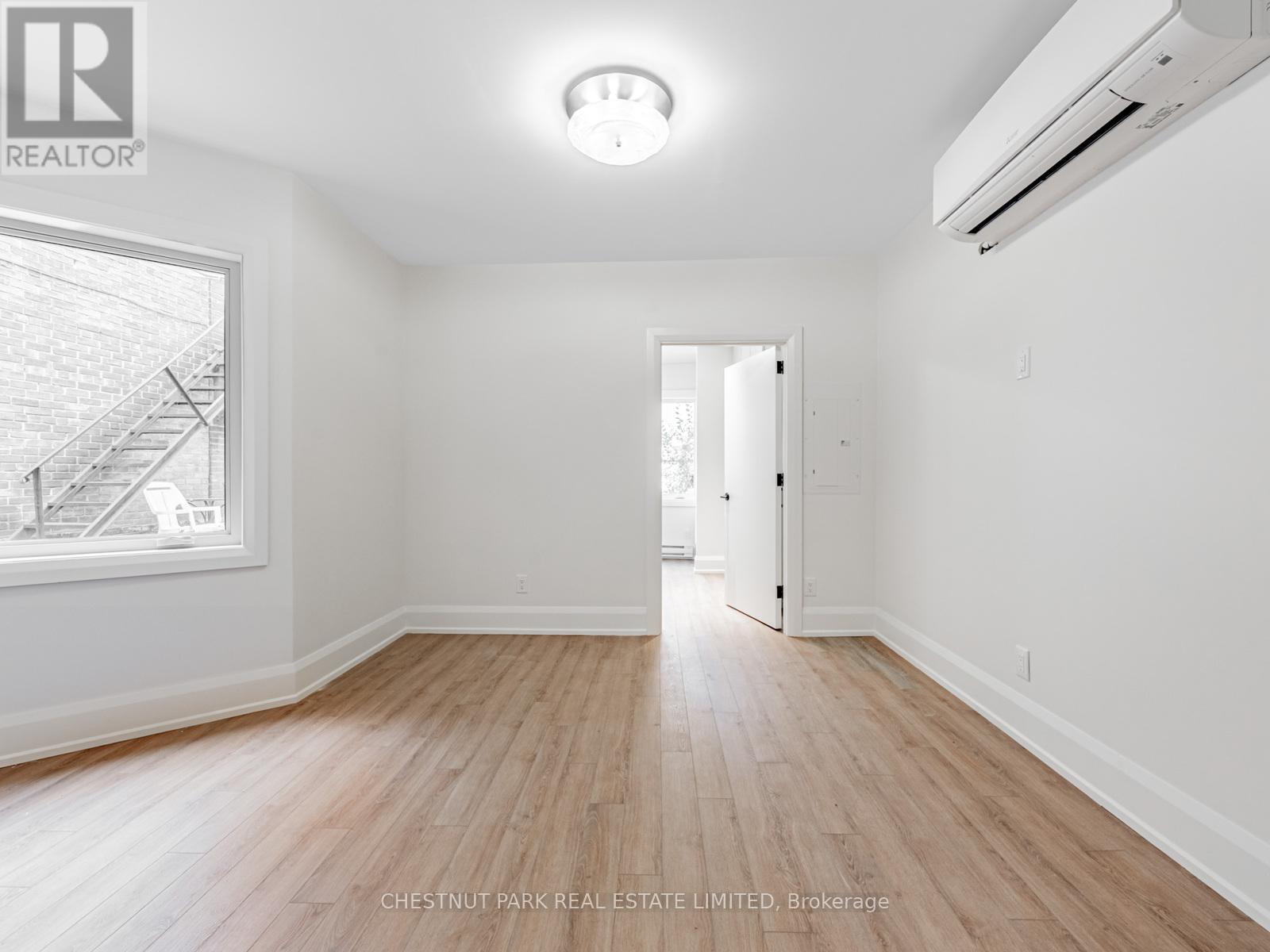 A spacious room with wooden flooring and white walls.