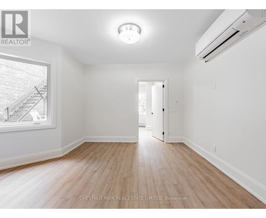 A spacious room with wooden flooring and white walls.