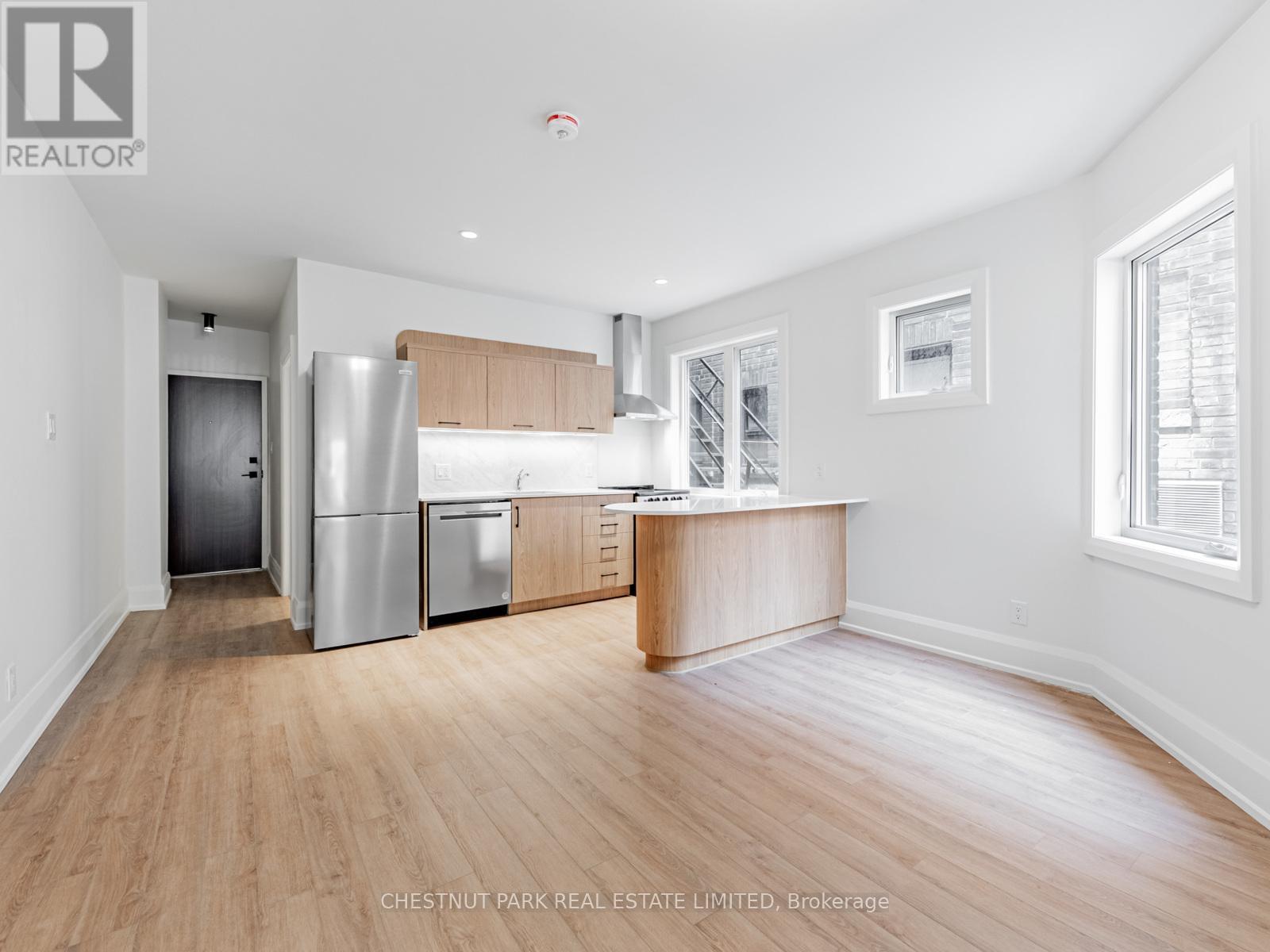 A kitchen with a refrigerator, oven, and cabinets.