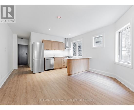 A kitchen with a refrigerator, oven, and cabinets.