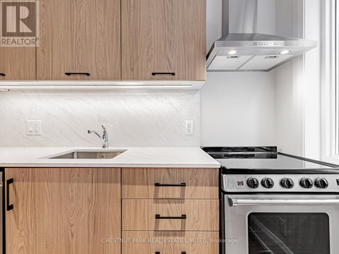A modern kitchen with wooden cabinets and a stainless steel oven.