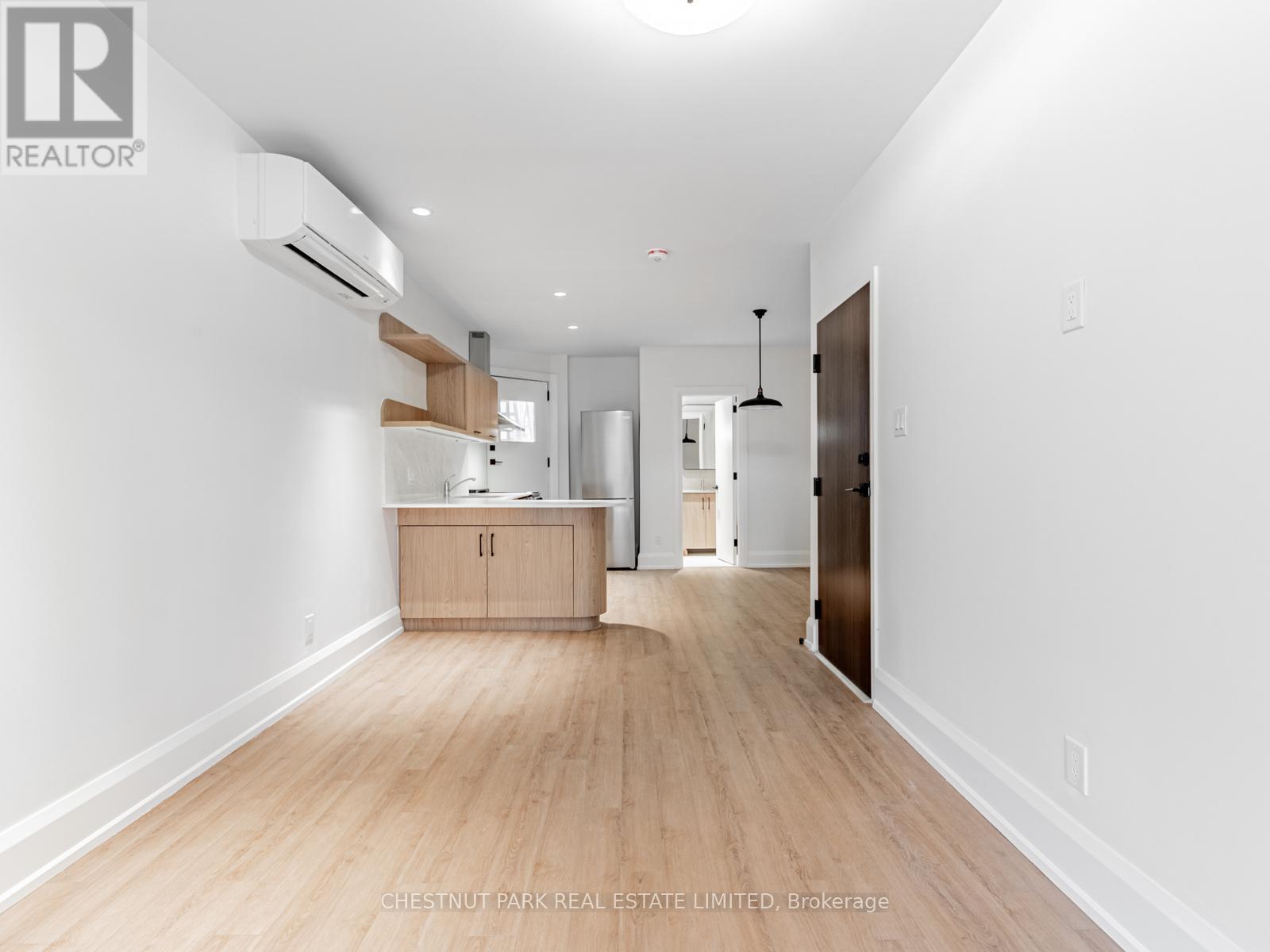 A spacious room with wooden flooring and white walls.