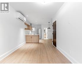 A spacious room with wooden flooring and white walls.