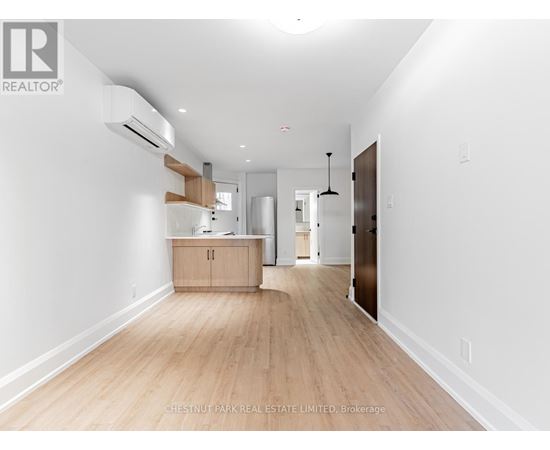 A spacious room with wooden flooring and white walls.