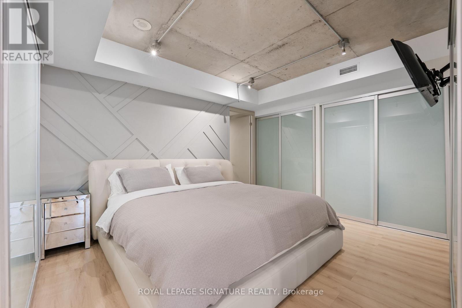 A bedroom with a large bed and a flat screen TV mounted on the wall.