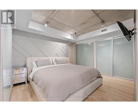 A bedroom with a large bed and a flat screen TV mounted on the wall.