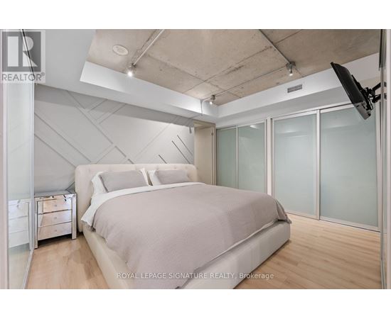 A bedroom with a large bed and a flat screen TV mounted on the wall.
