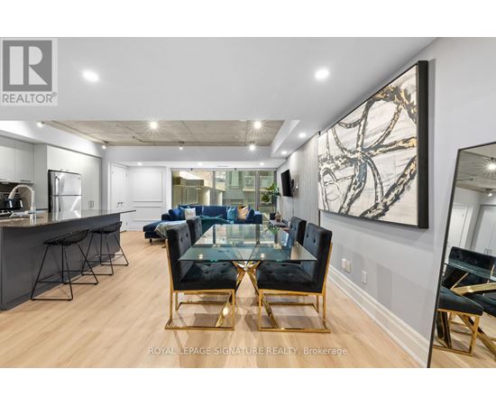 A modern living room with a glass table and black chairs.