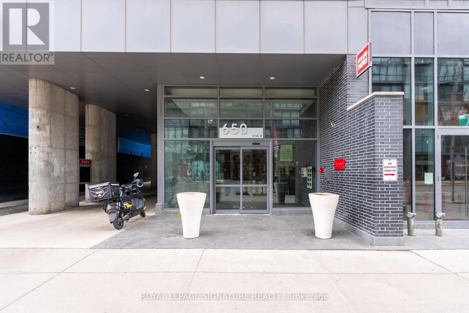 A motorcycle is parked outside a building with a glass door entrance.