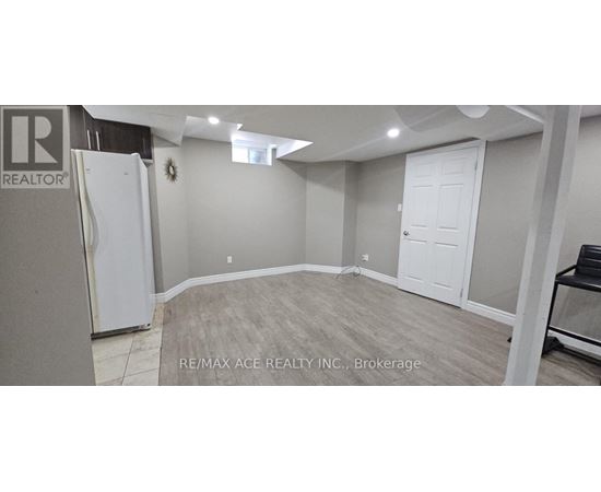 A spacious room with a white door and a fridge in the corner.