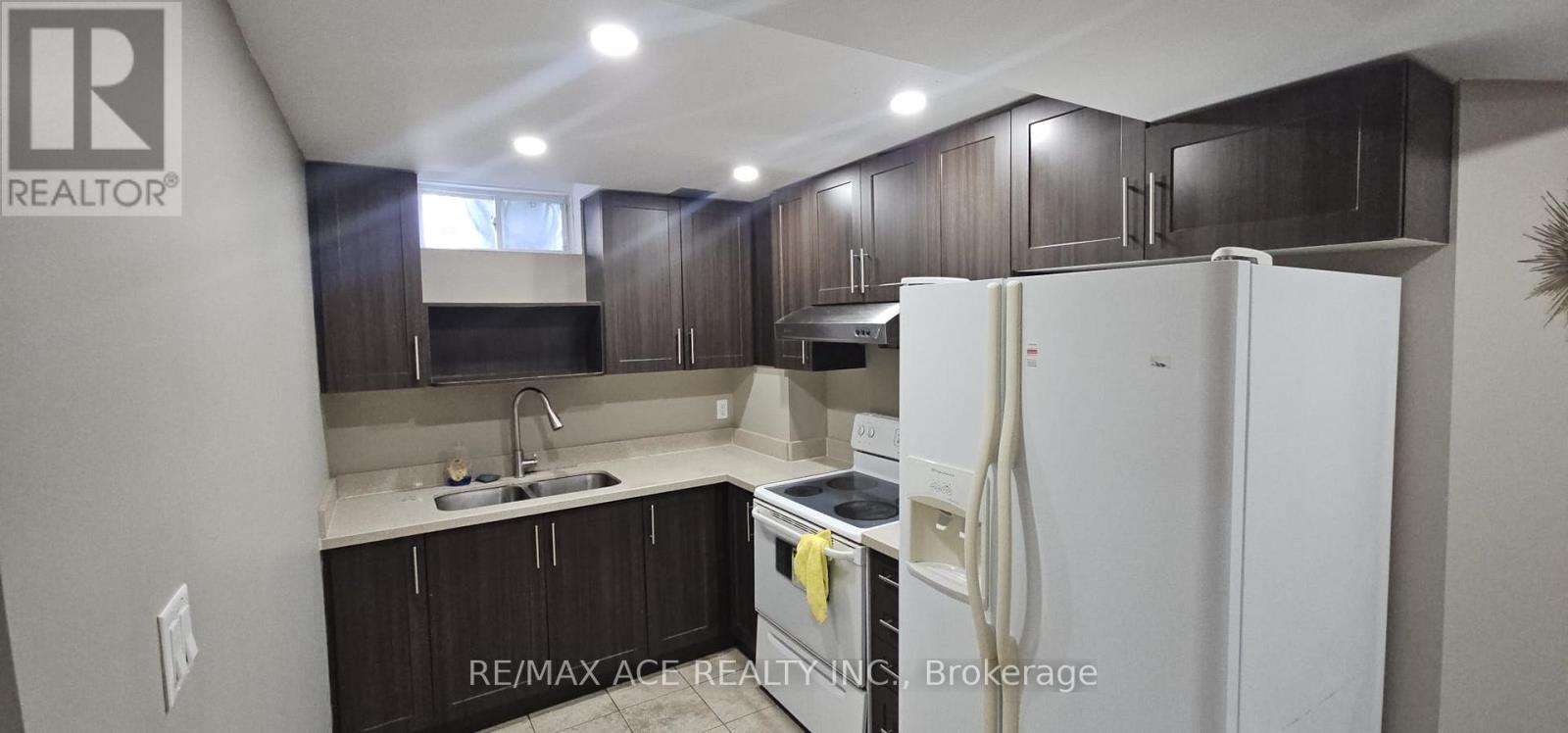 A kitchen with a white refrigerator and dark brown cabinets.