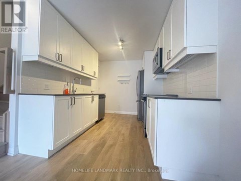 A kitchen with white cabinets and a wooden floor.