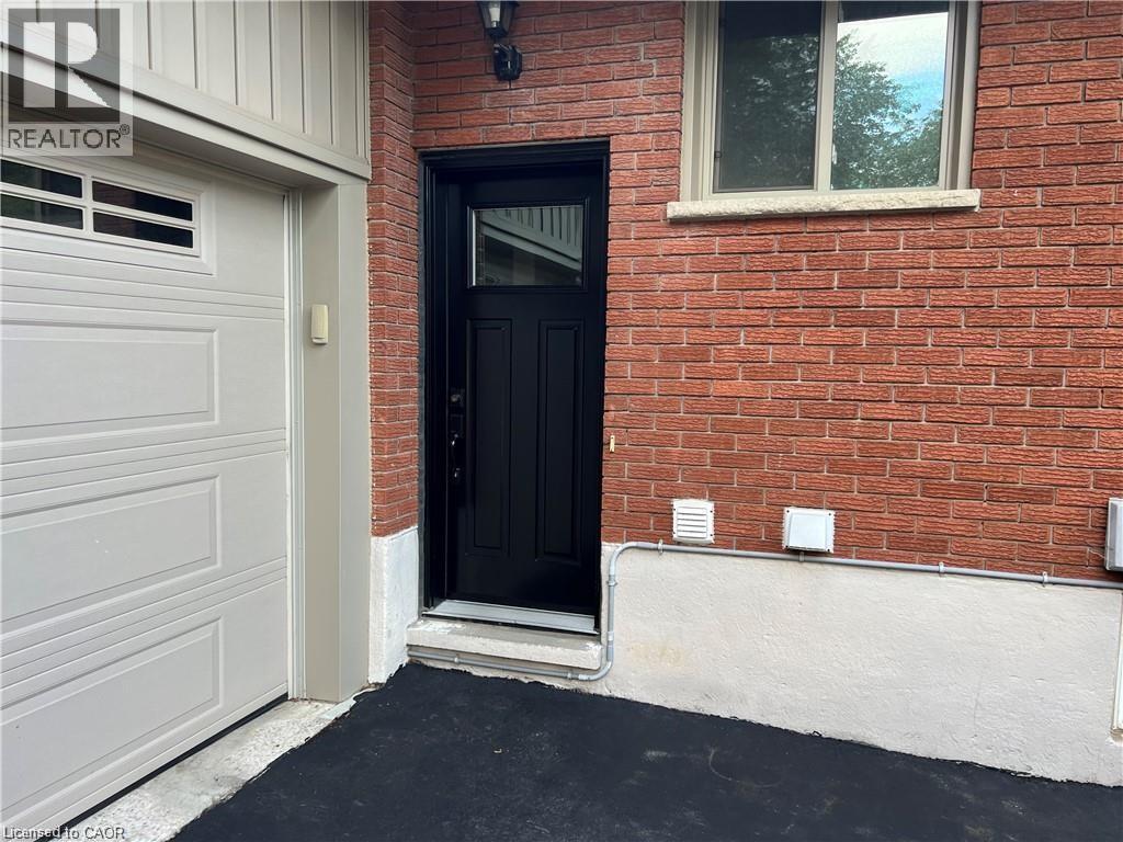 A black door is on the left side of a red brick house.
