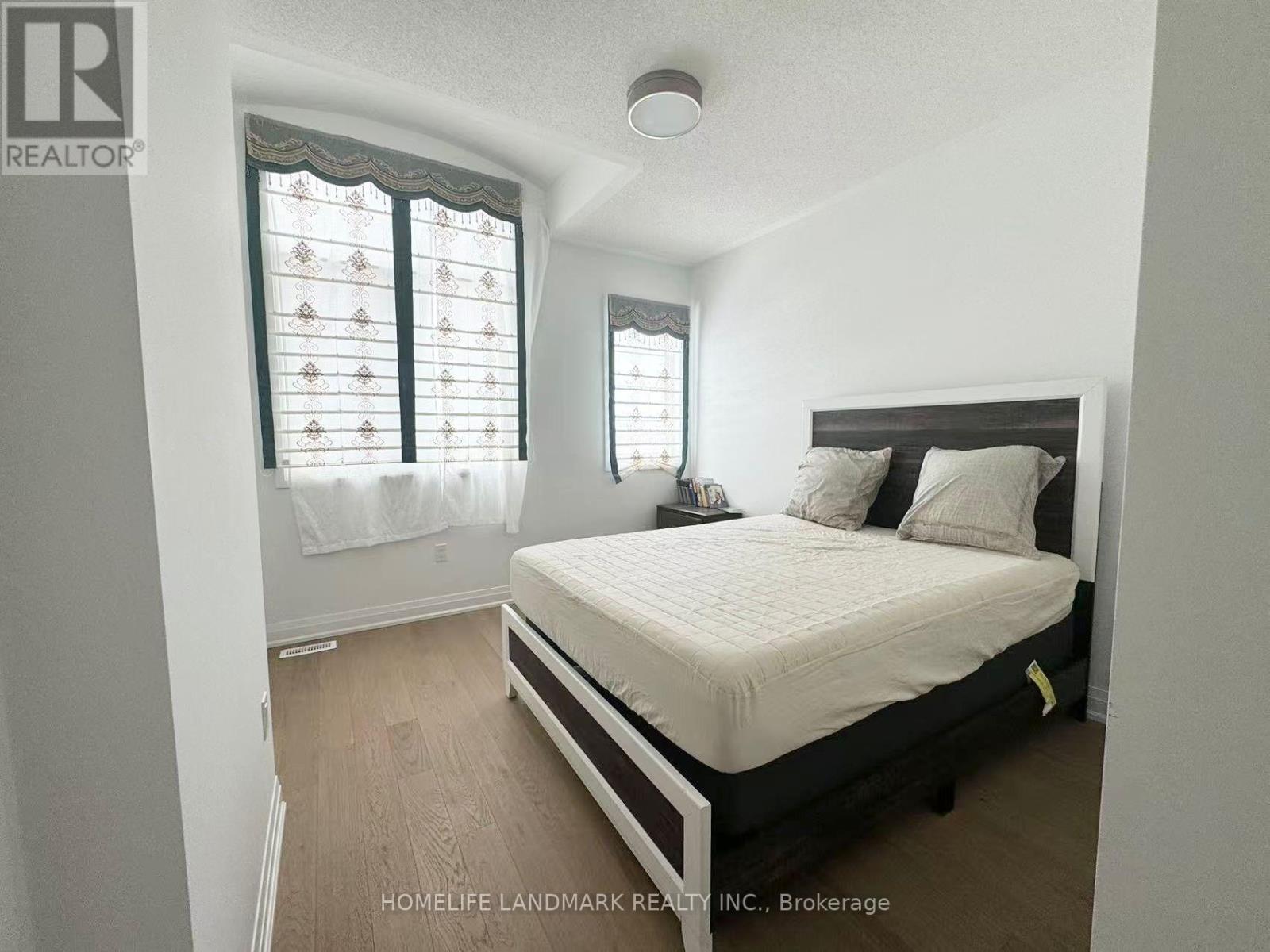 A bedroom with a bed, nightstand, and window with blinds.