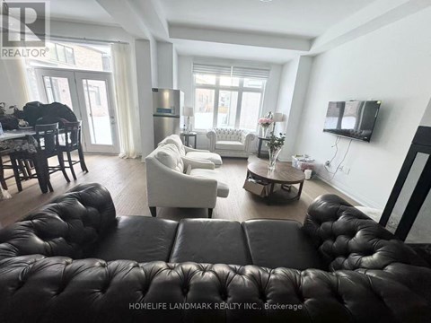 A living room with a black leather couch and a television on the wall.