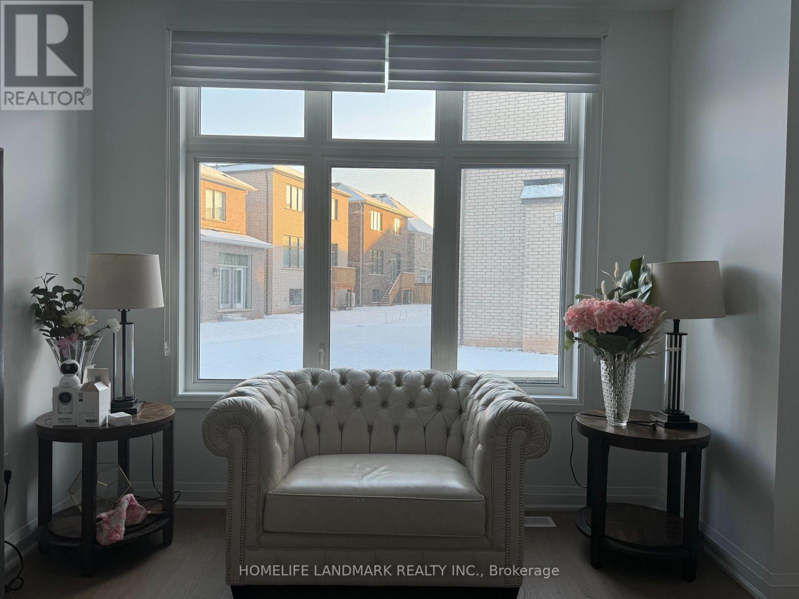 A white chair sits in front of a window with a view of apartment buildings.