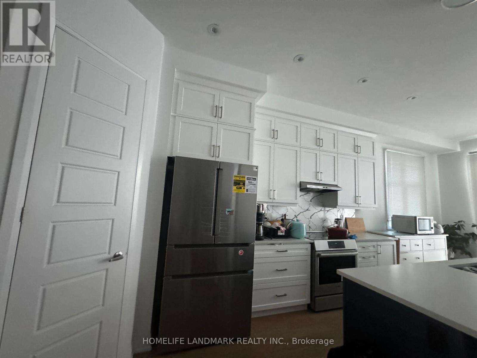 A kitchen with white cabinets and a fridge.