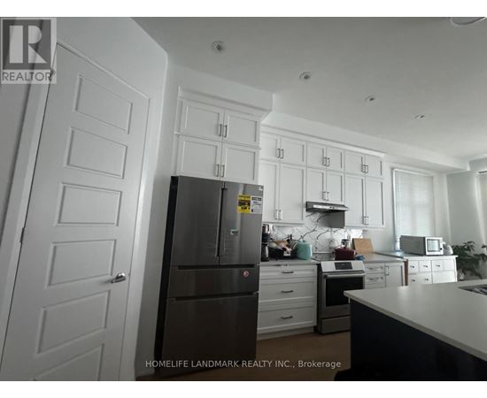 A kitchen with white cabinets and a fridge.