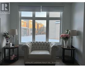 A white chair sits in front of a window with a view of apartment buildings.