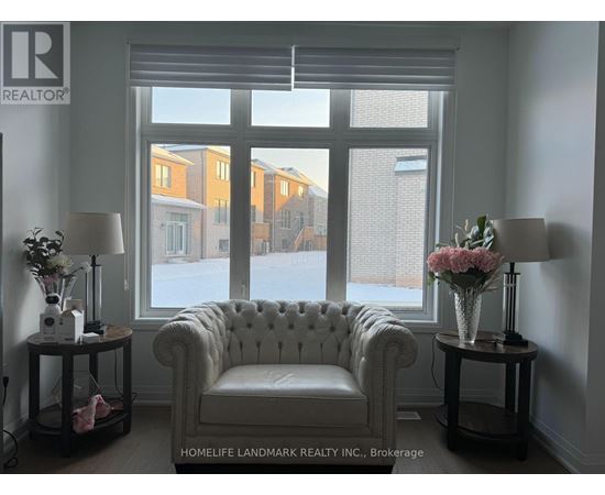 A white chair sits in front of a window with a view of apartment buildings.