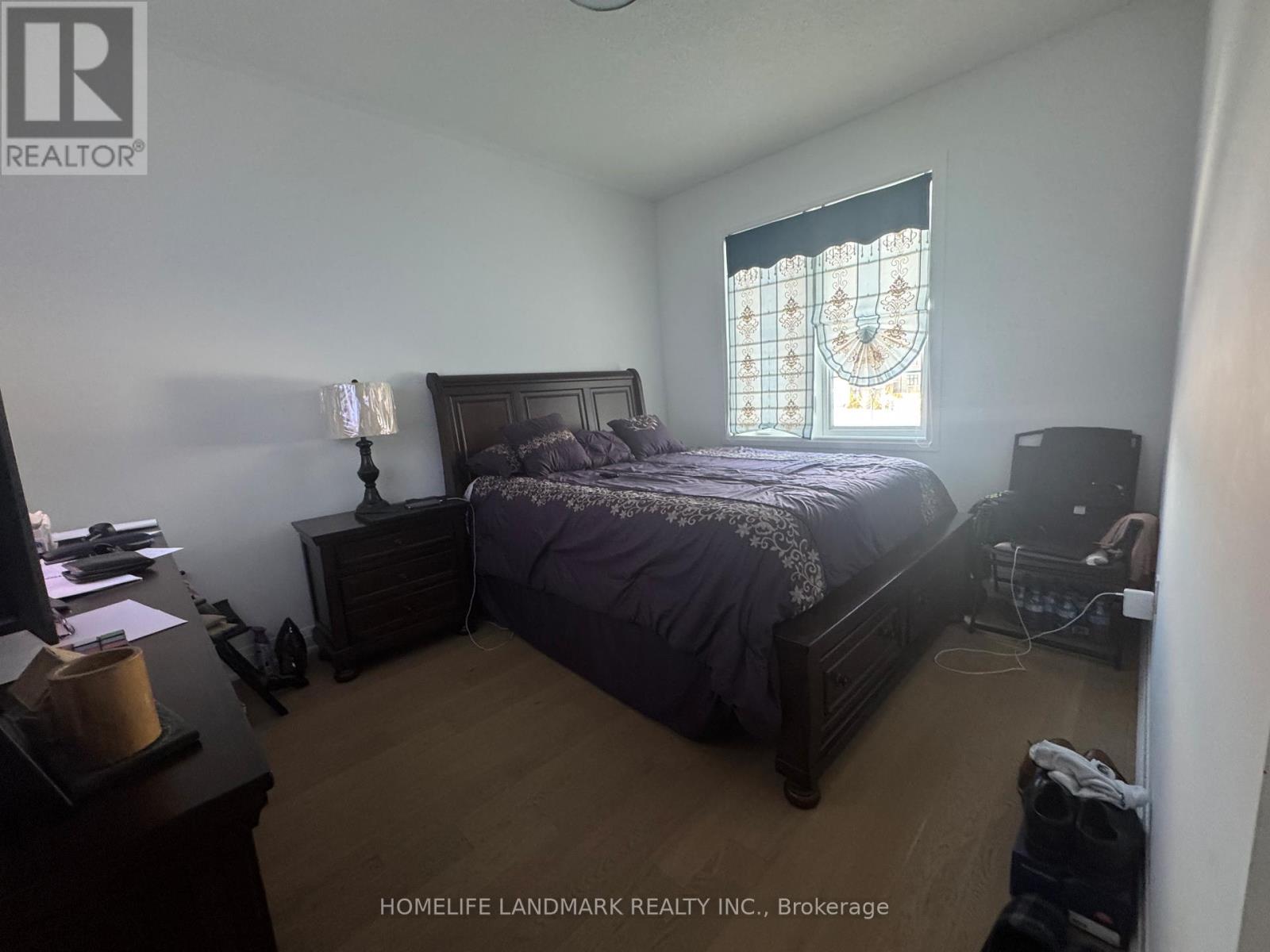 A bedroom with a bed, nightstand, and window with a stained glass design.