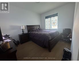 A bedroom with a bed, nightstand, and window with a stained glass design.