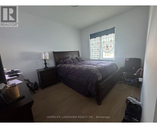 A bedroom with a bed, nightstand, and window with a stained glass design.