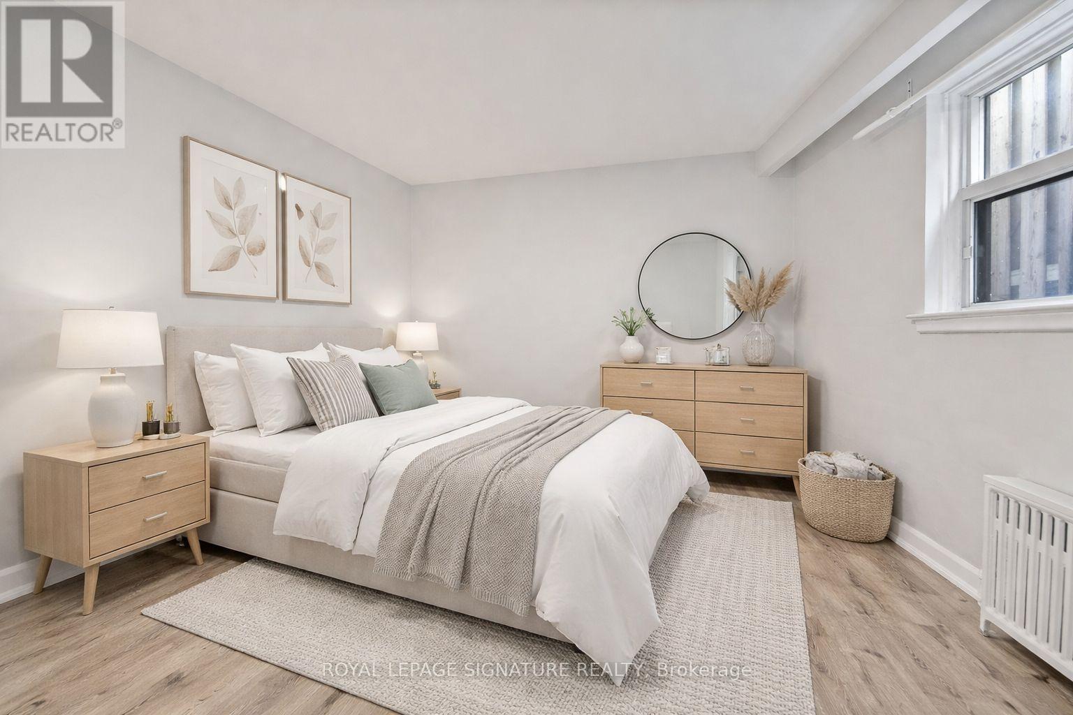 A bedroom with a bed, nightstands, and a window.