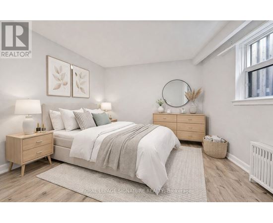 A bedroom with a bed, nightstands, and a window.