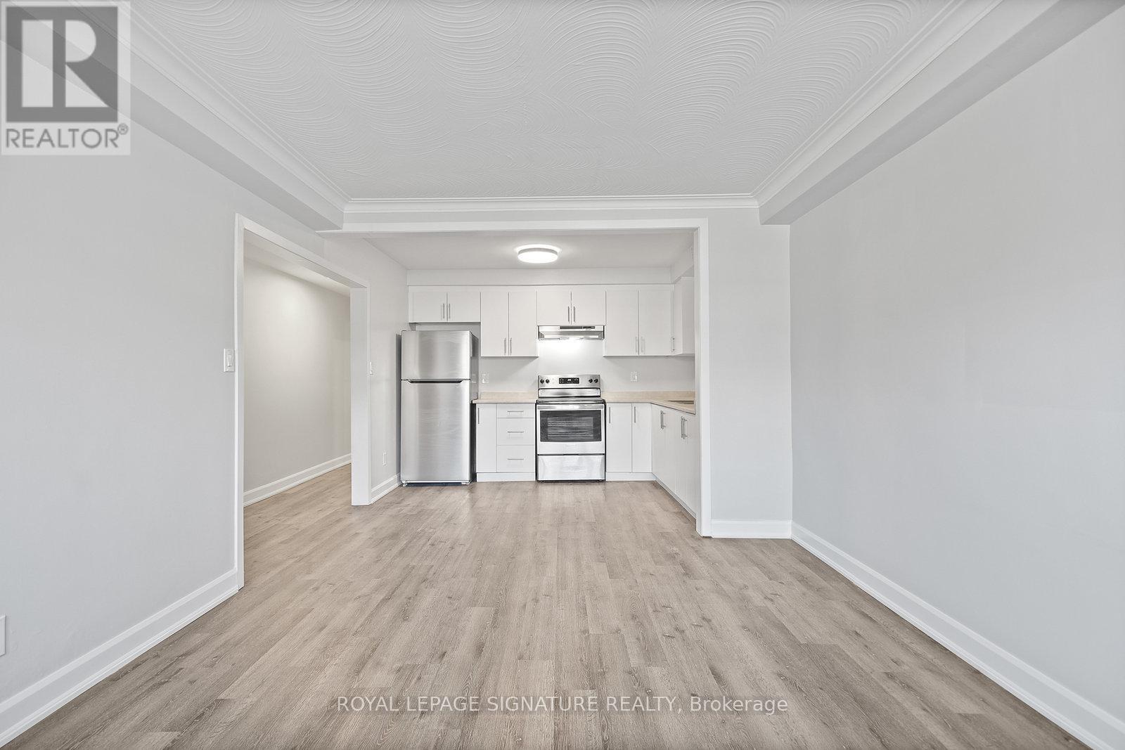 A kitchen with white cabinets and a stainless steel refrigerator.