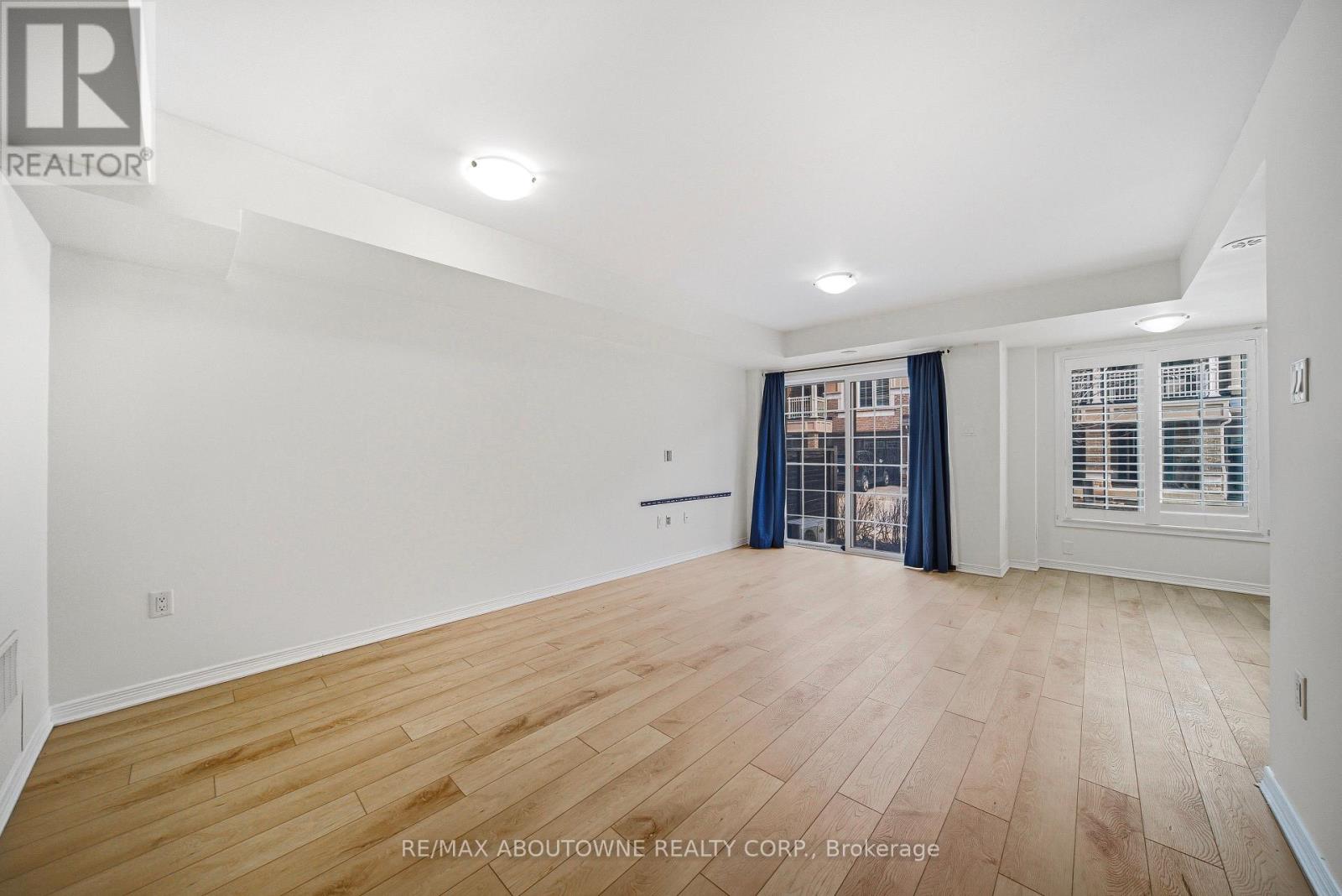 A spacious room with wooden flooring and white walls.
