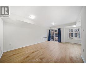 A spacious room with wooden flooring and white walls.