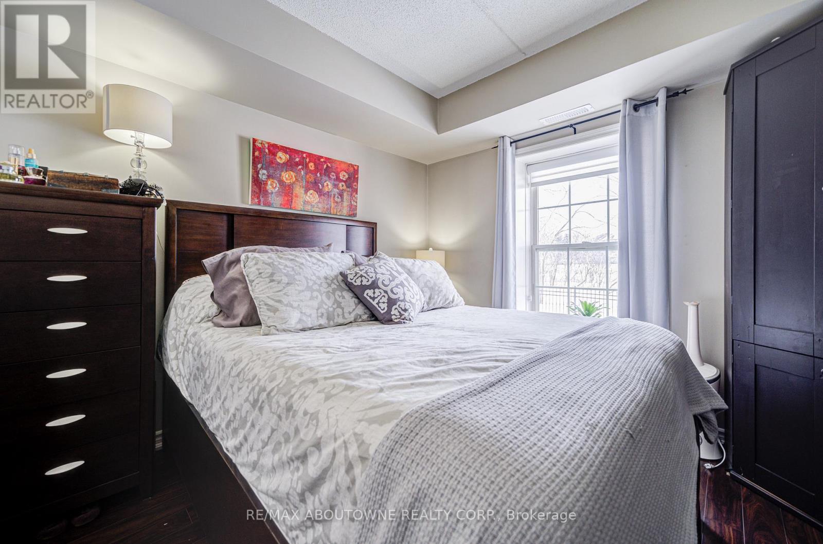 A bedroom with a bed, nightstand, and a painting on the wall.