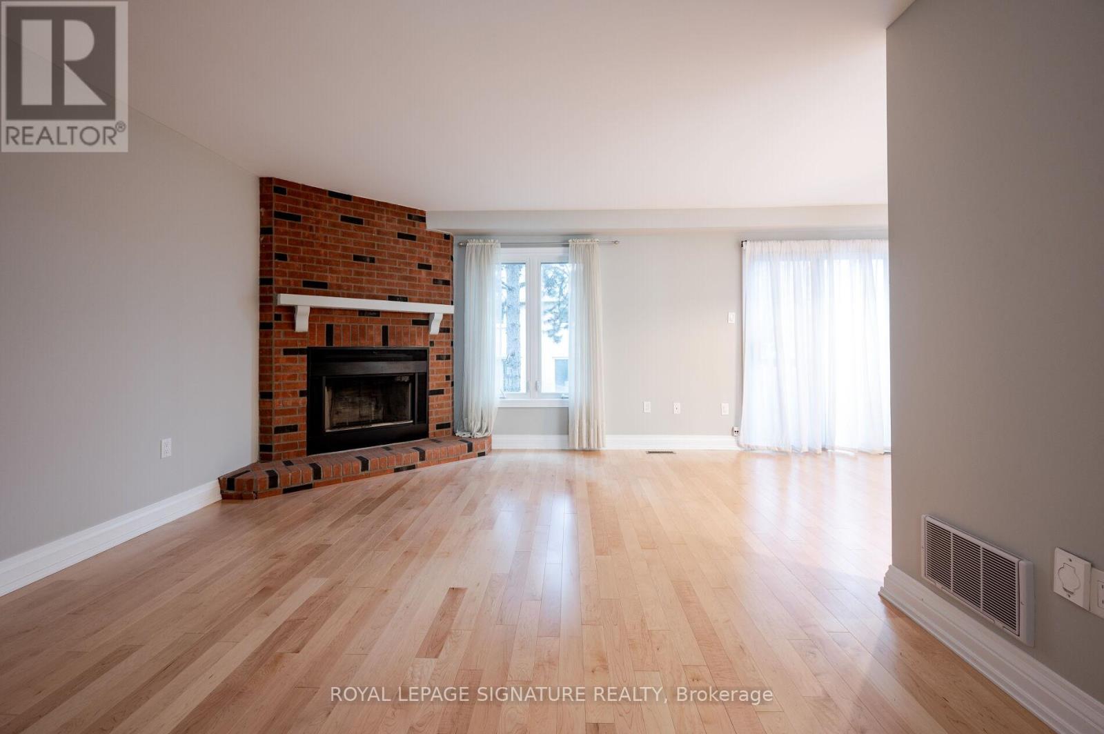 A spacious room with a fireplace and wooden floors.